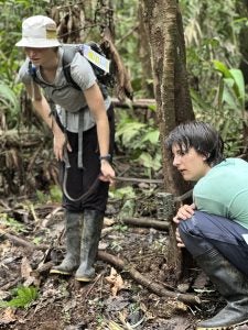 Two women set up a camera trap around a tree.