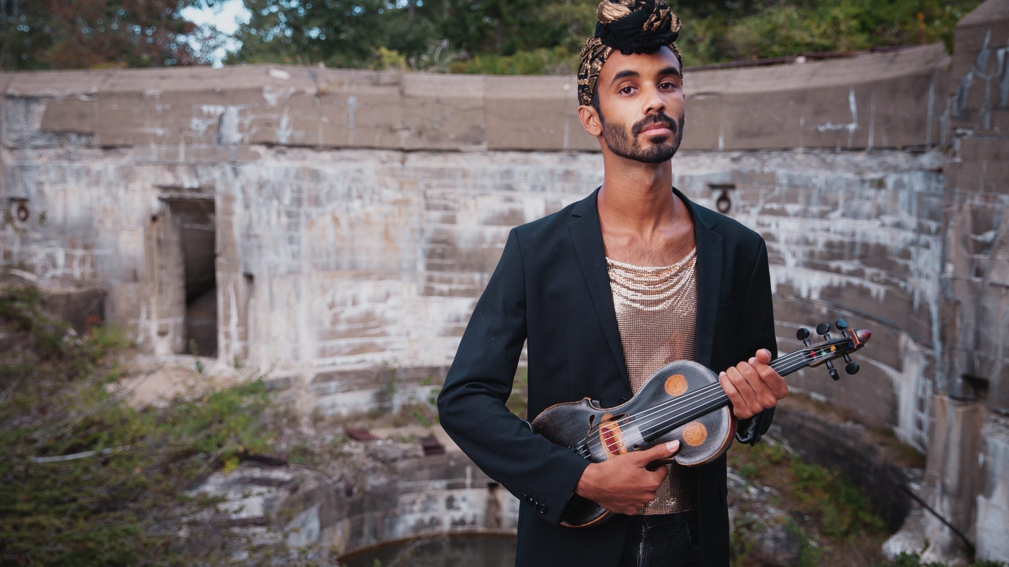 Jake Blound, standing with instrument in front of stone wall.