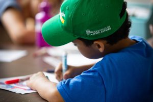 A shot from behind of a boy writing with a marker.