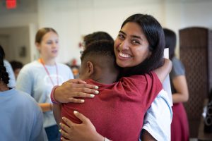 A young woman with a smile on her face hugs a boy in a red shirt