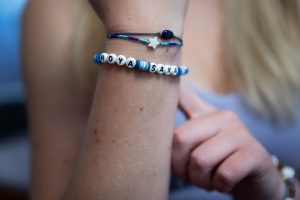 A close-up of a beaded bracelet on a young woman's arm that says "Hoya Saxa!"