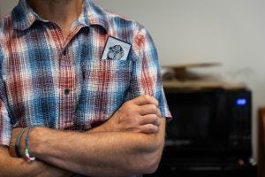 A close-up of a short-sleeve button-down shirt with a ticket to a Hoyas basketball game in a man's pocket.