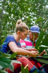 Mae works with a Maijuna man to weave materials for a hut in the rainforest