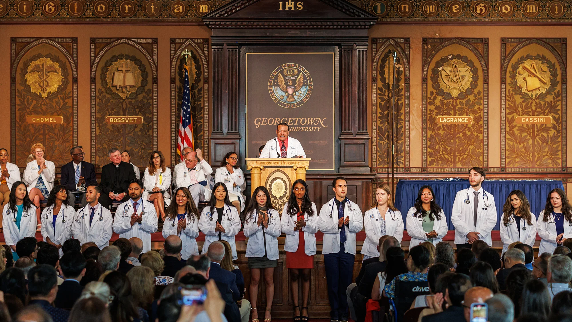 Students in white coats in a well-lit hall.