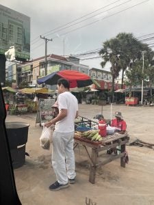 A man on the sidewalk on a busy street in Asia.