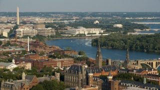 An aerial view of Georgetown&#039;s campus with the Washington monument and Potomac in the background.