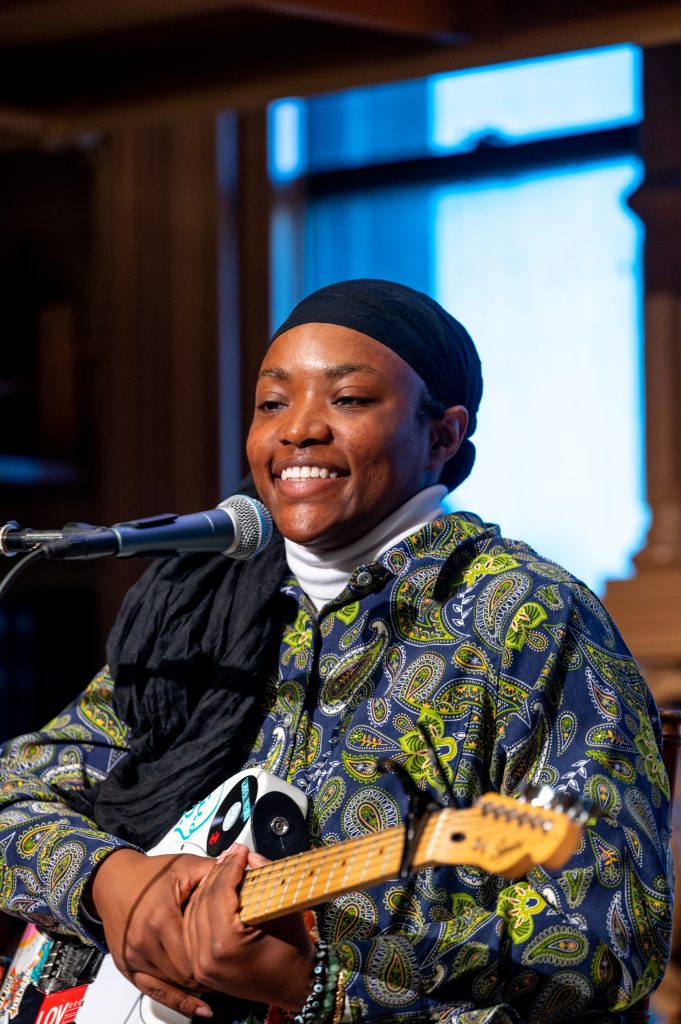 A student sings and smiles into a microphone while playing the guitar at a showcase that celebrated the disability community and the arts on Georgetown's campus.