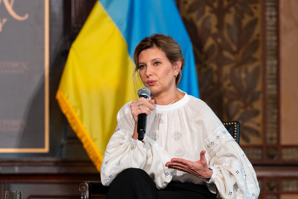The First Lady of Ukraine speaks on the stage of Gaston Hall with the blue and yellow Ukrainian flag behind her.
