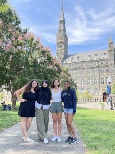 A group of students stand outside the clocktower of Healy Hall.