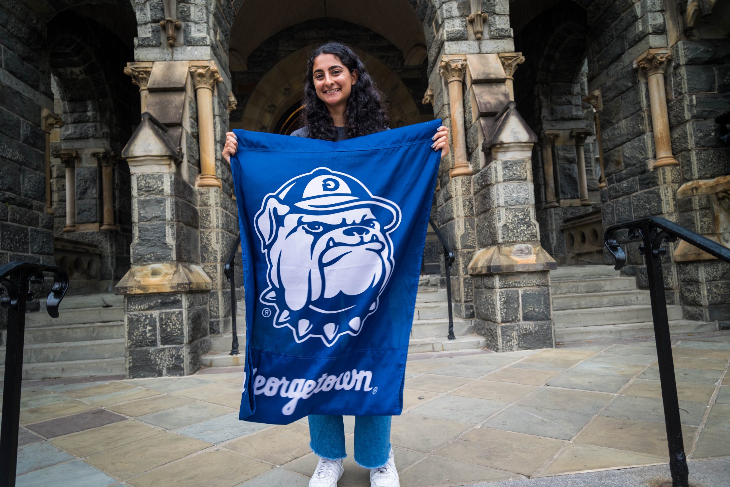 Zehra Mizra with a GU flag in front of Healy Hall