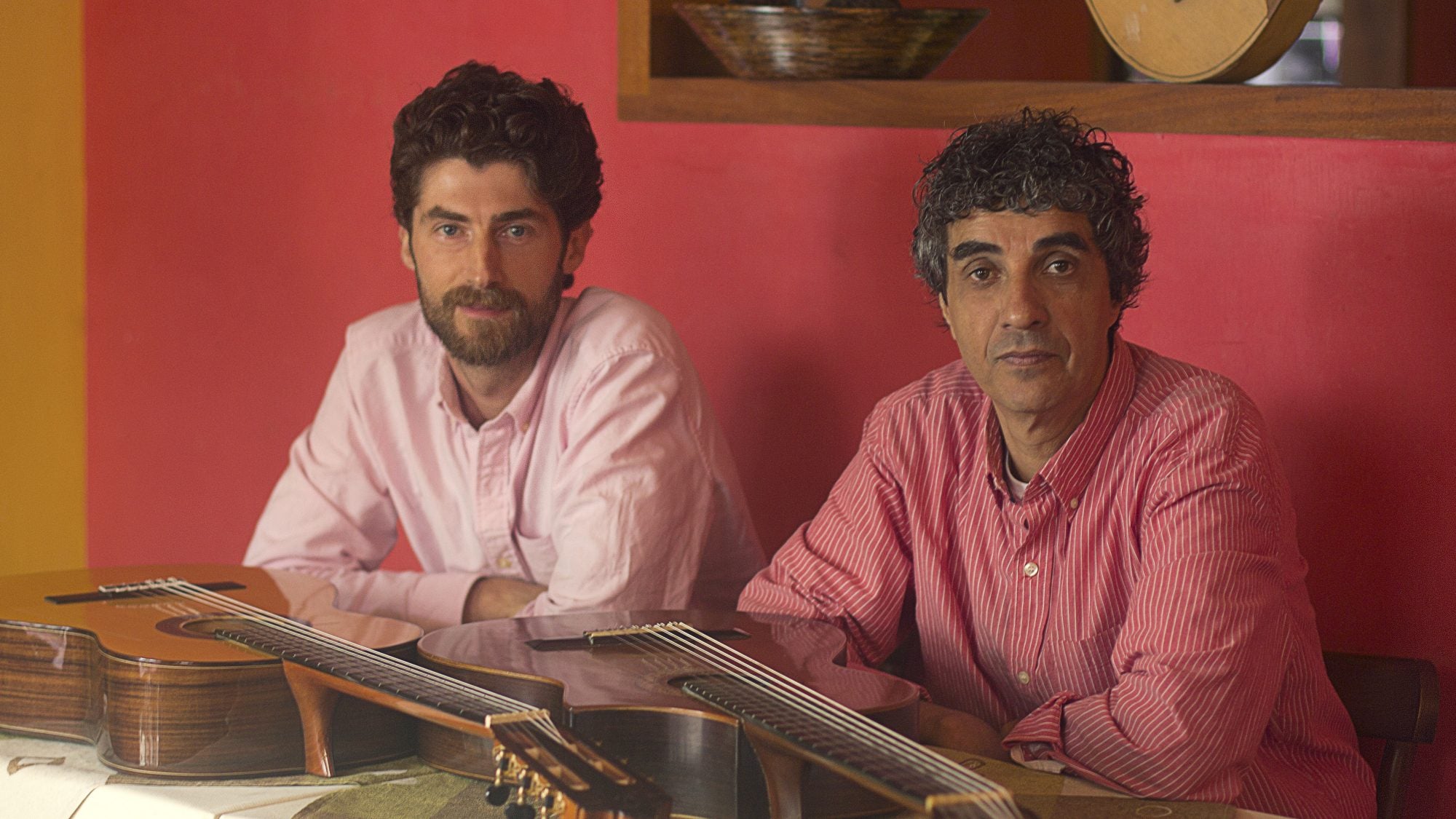 Rogerio and Stephen, sitting in front of guitars.