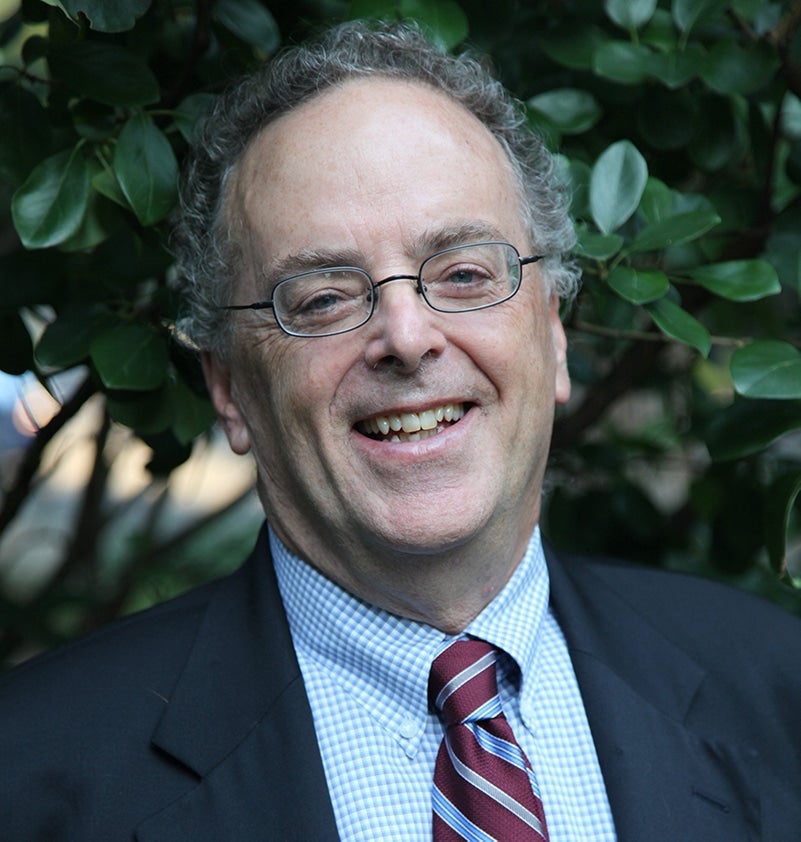 Steve Khon, standing in front of tree, wearing jacket and tie.