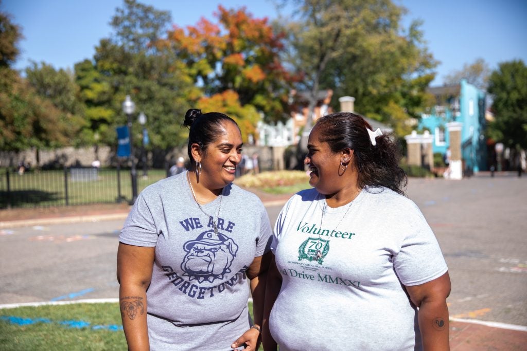 Two sisters smile at each other in Healy Circle on Georgetown's Main Campus.