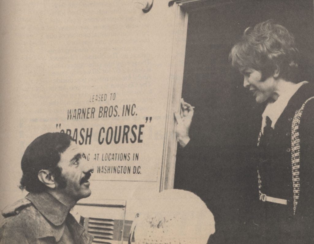 Black and white photo of man talking to a woman by a production truck