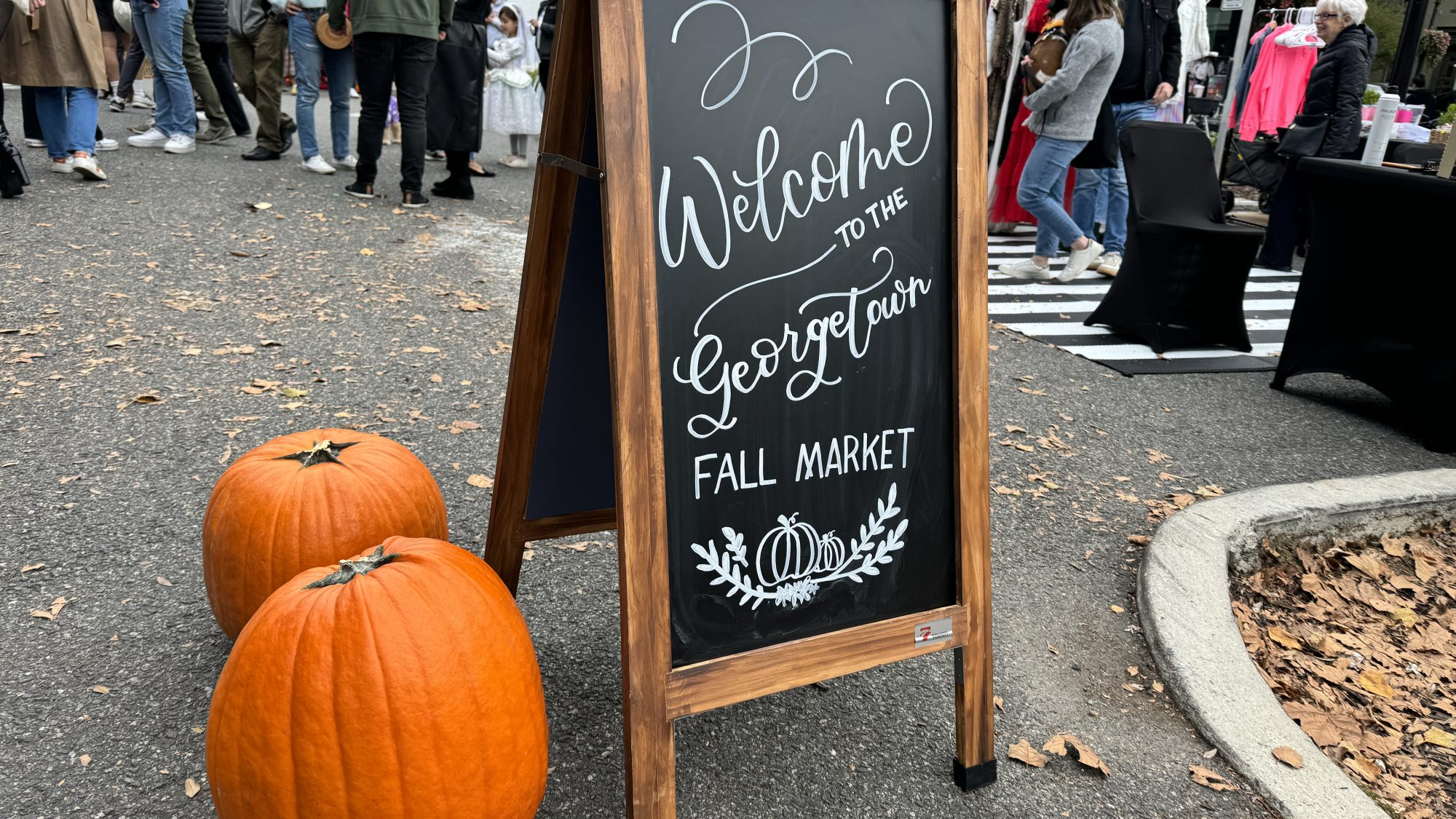 Pumpkins and chalkboard sign that reads &quot;Welcome to the Georgetown Fall Market&quot; in cursive
