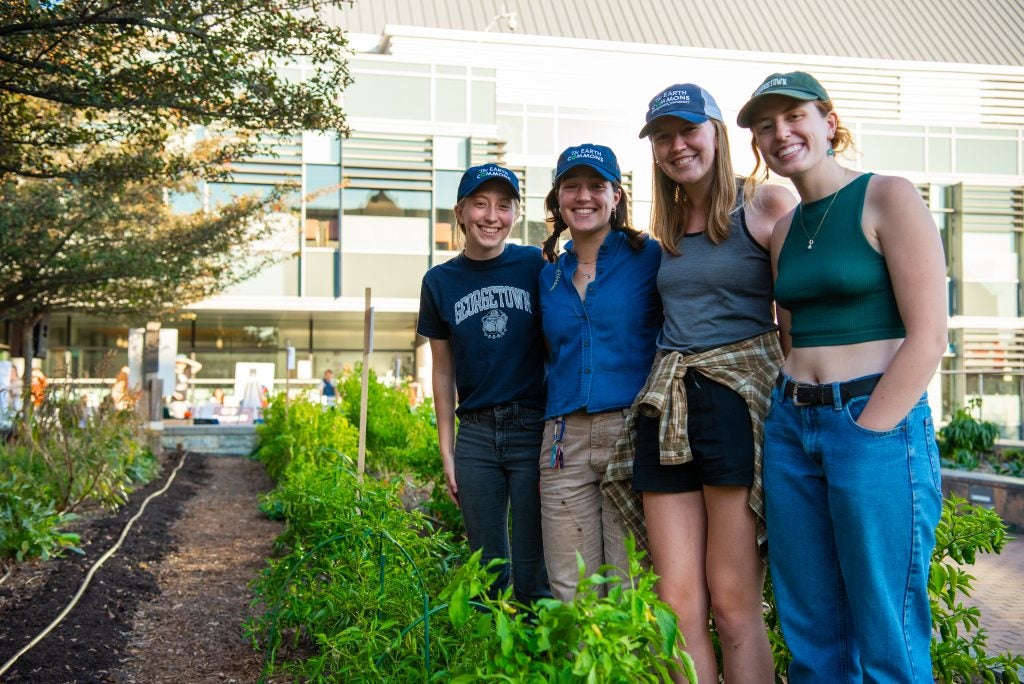 Four students stand together at the Hoya Harvest Garden