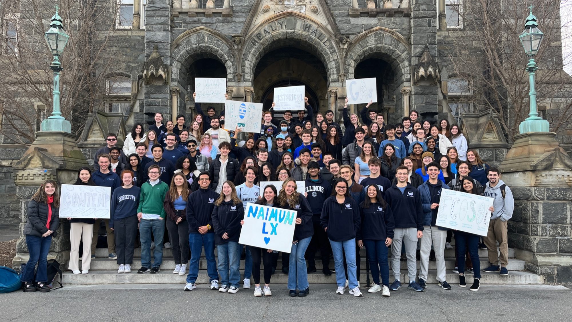 NAIMUN students stand on Healy steps for a group photo, holding NAIMUN signs