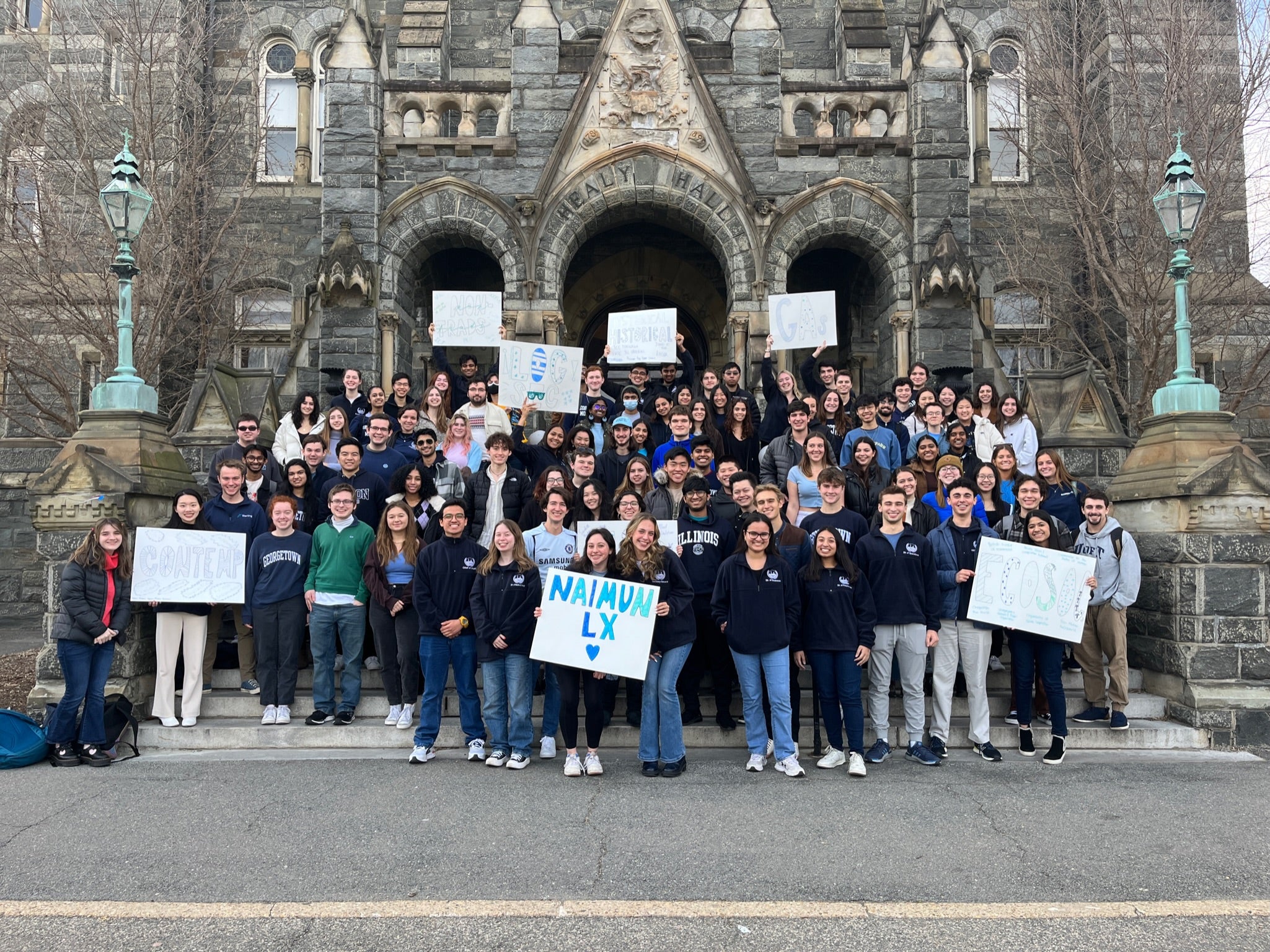 NAIMUN students stand on Healy steps for a group photo, holding NAIMUN signs