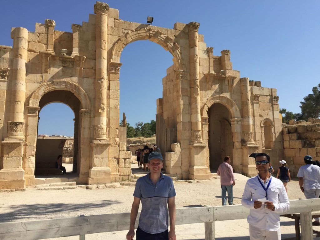 Man standing in front of some ruins outside