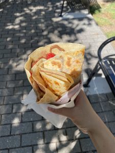 Person holds Nutella crepe with strawberries