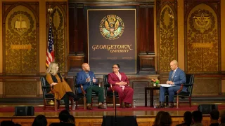 Panelists sitting down on stage in Gaston Hall