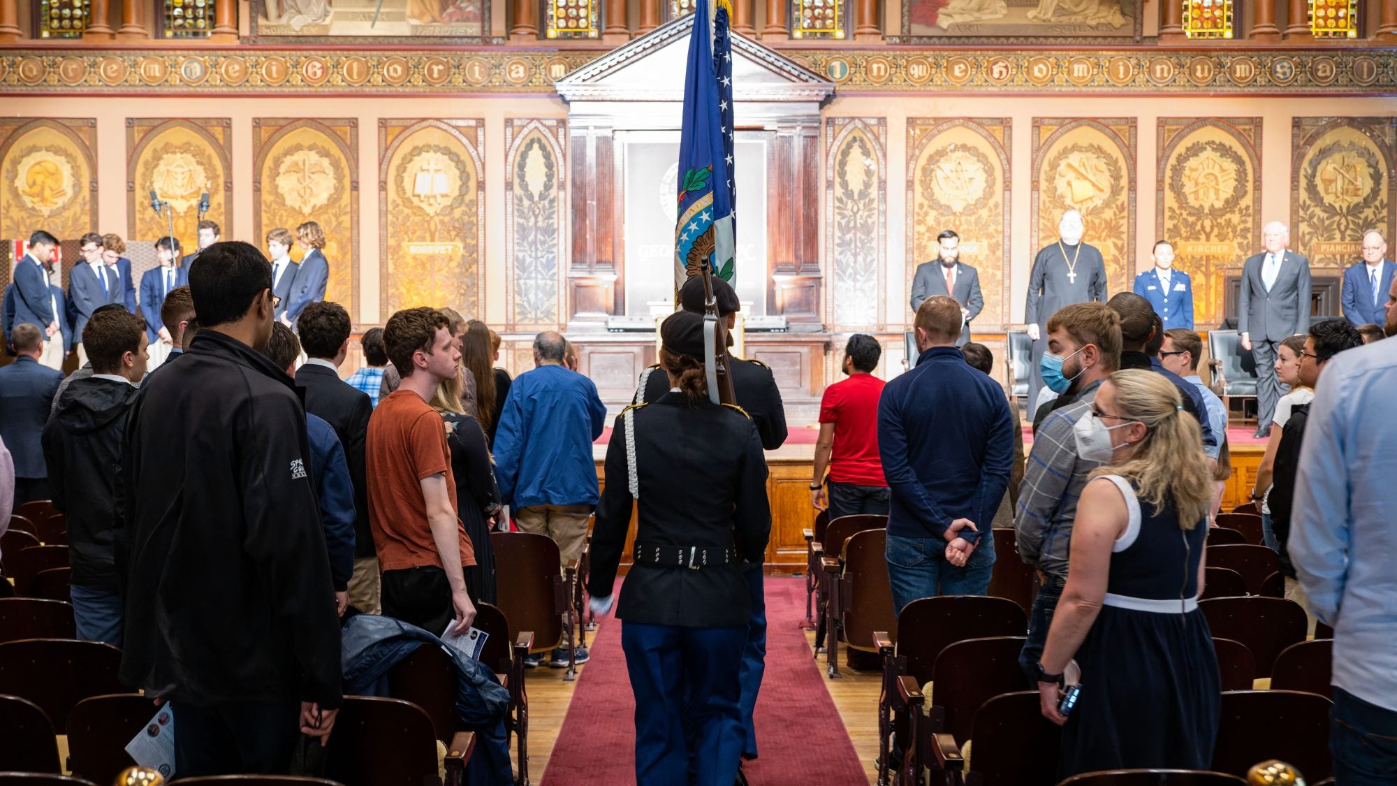 People in military dress waking down Gaston Hall with flags