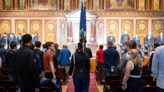 People in military dress waking down Gaston Hall with flags