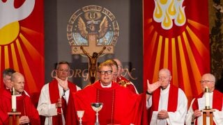 Catholic priest in red garments celebrates Mass
