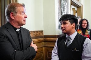 A Catholic priest talks to a student indoors