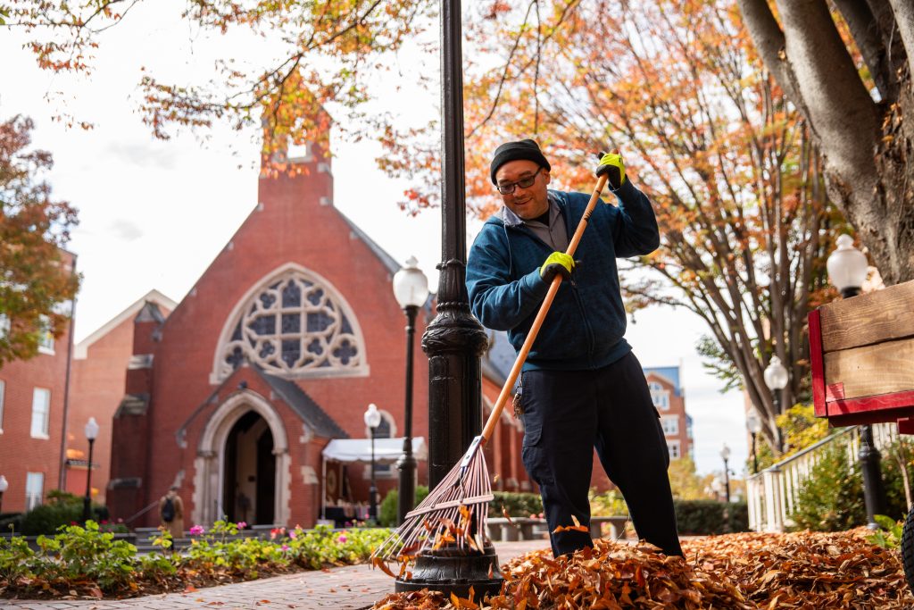 A landscaper rakes leaves in front of Dahlgren Chapel at Georgetown.