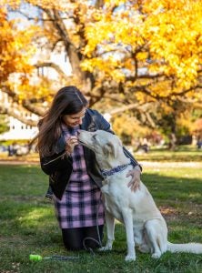 Woman feeding her dog a treat on a fall day