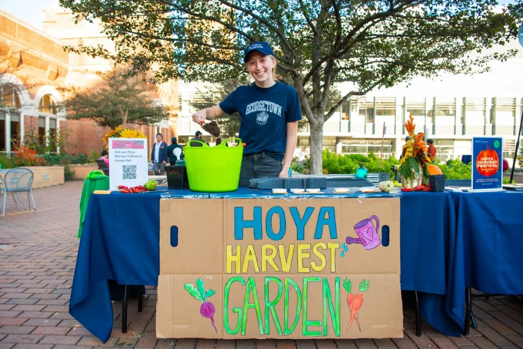 Student in front of a table with a sign for Hoya Harvest Garden