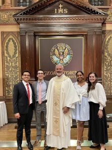 Group of students standing with a Catholic priest