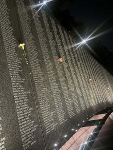 A list of names inscribed at the Korean War Veterans Memorial, with flowers left between each column of names