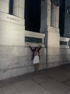 Mara stands with her arms wide between the Hawaii and DC  monuments at the World War 2 Memorial