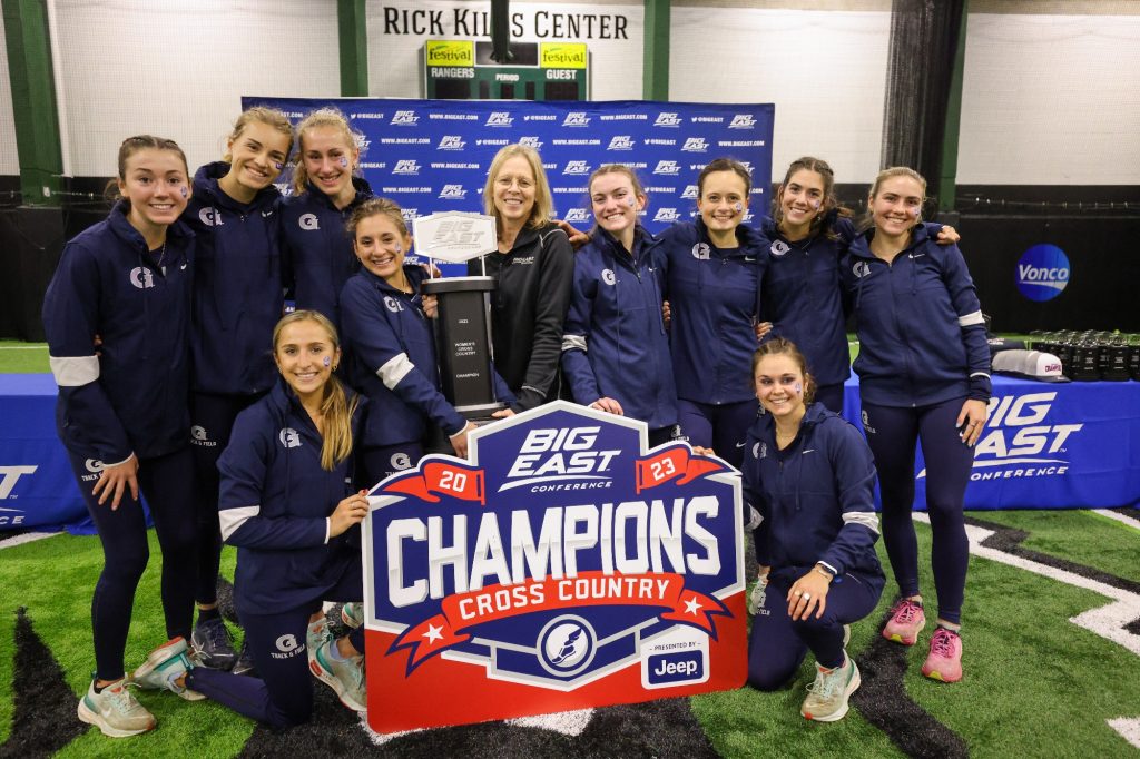 Women's cross country team in front of a champions sign