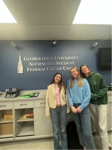 3 girls stand smiling in front of the Georgetown University Alumni and Student Federal Credit Union branch sign