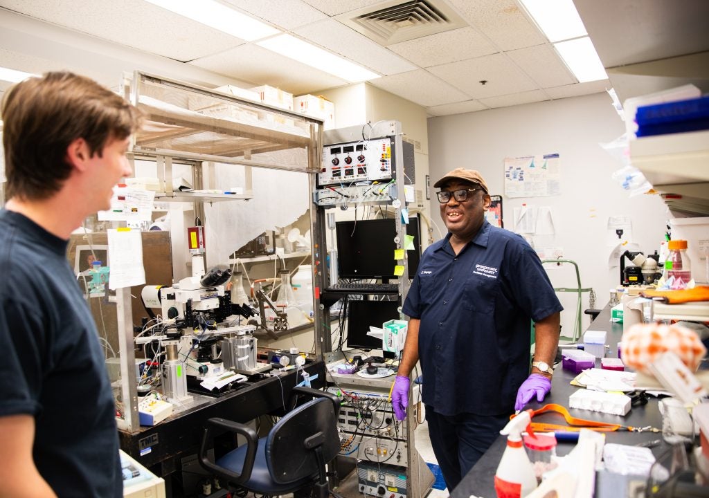 A custodian and a lab technician laugh together in a lab at Georgetown.
