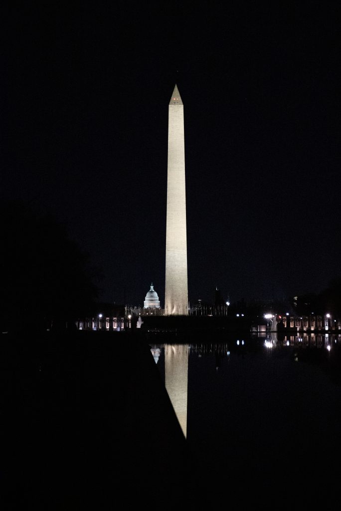 A nighttime photo of the Washington monument, with the Capitol building behind it