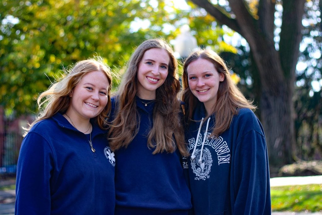 Three student volunteers for Georgetown's student-run ambulance service smile together.