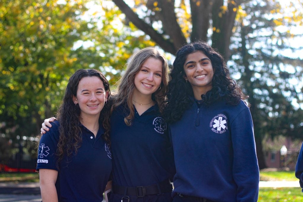 Three student volunteers for Georgetown's student-run ambulance service smile together.