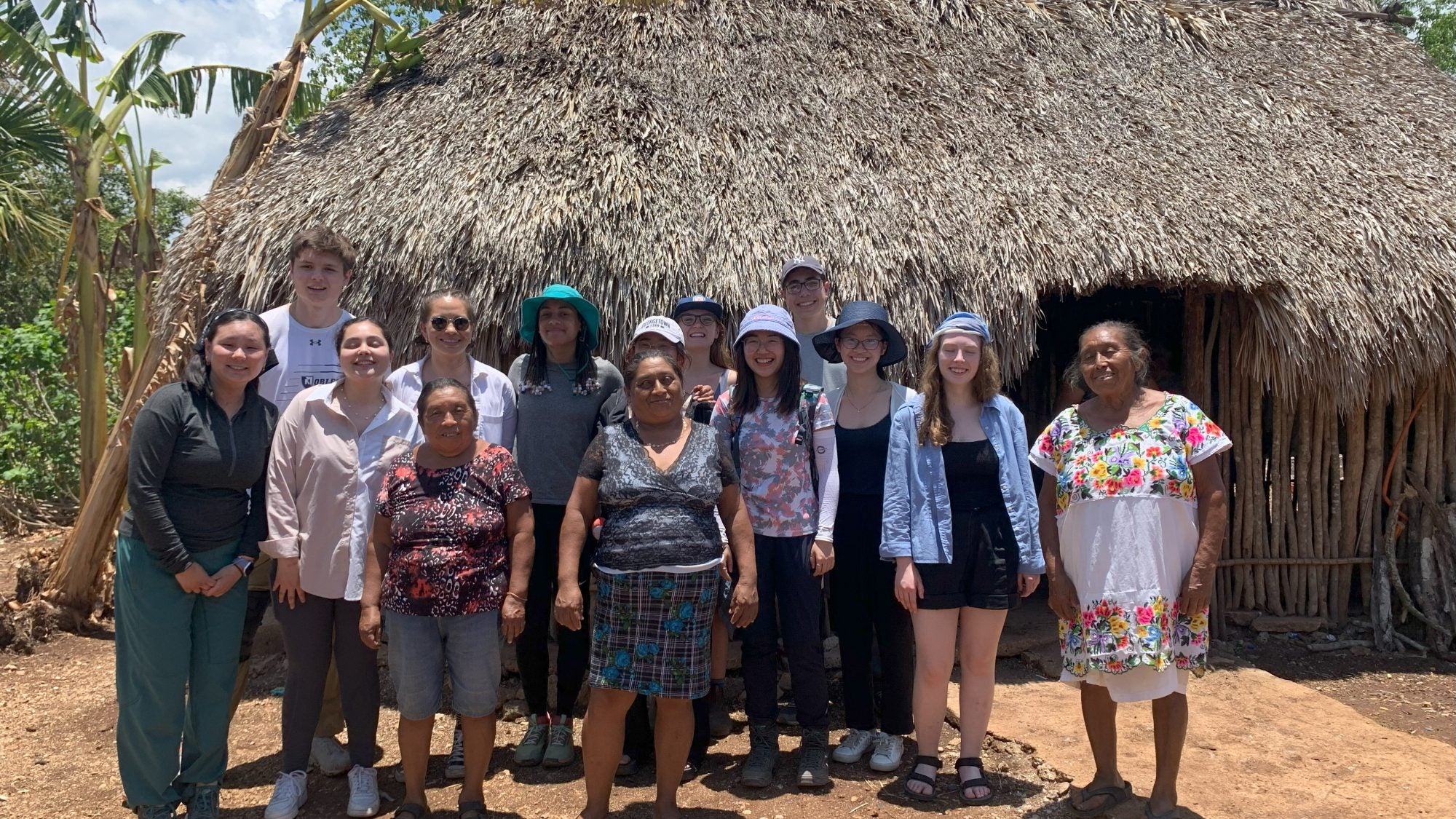 Group of students in front of a hut