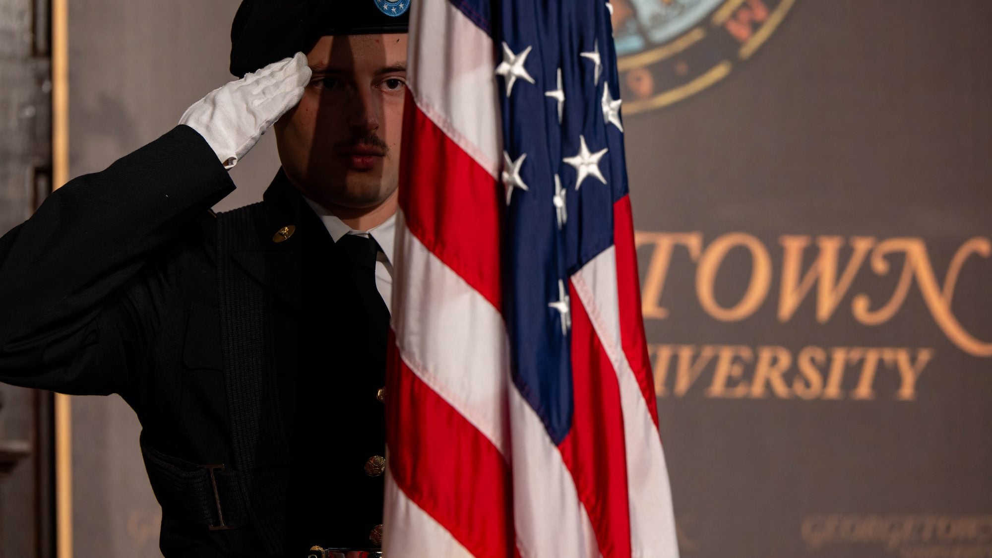 ROTC cadet saluting the American flag in Gaston Hall