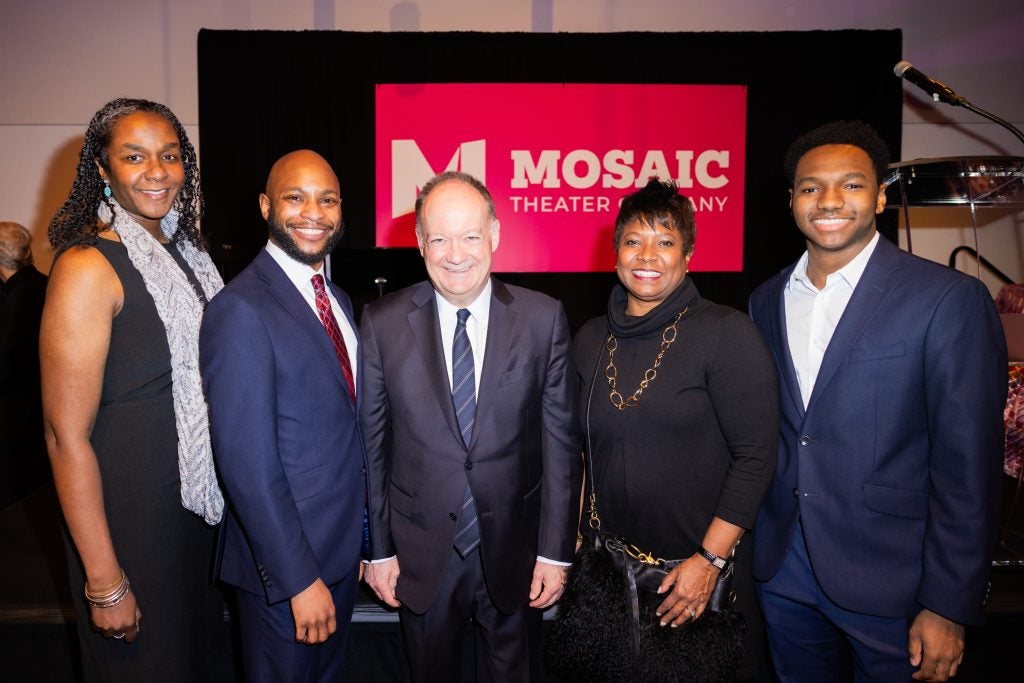 Two women and three men pose together in front of a red sign that says "Mosaic Theater Company" during an awards ceremony hosted by Georgetown.