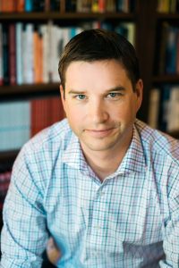 Cal Newport, an associate professor at Georgetown, wears a button-down shirt in front of a bookcase.