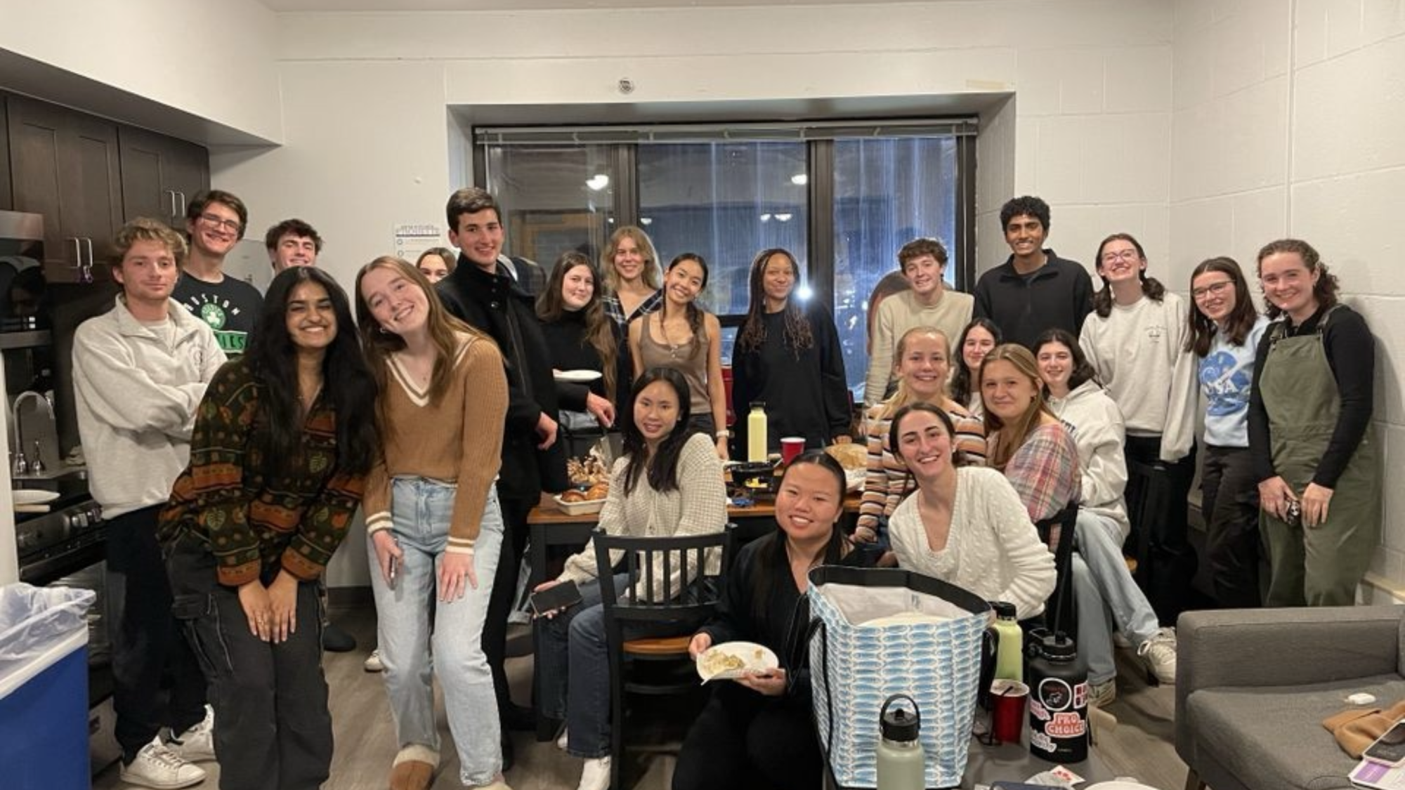 A group of students standing around a table for friendsgiving