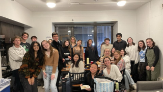 A group of students standing around a table for friendsgiving