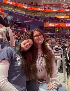 Two young women in a basketball stadium in the stands