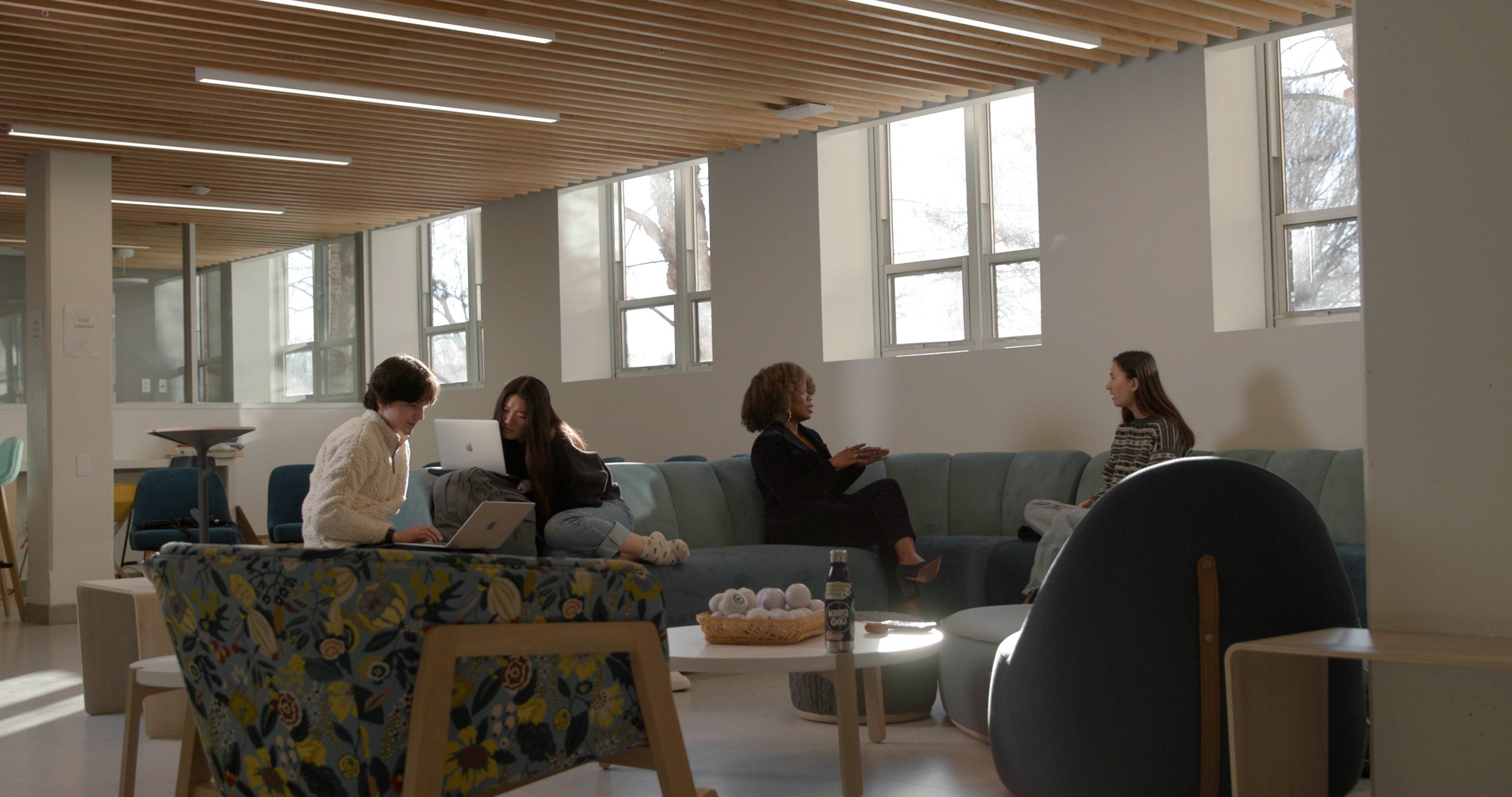 Several people sitting in a lounge space on chairs and couches