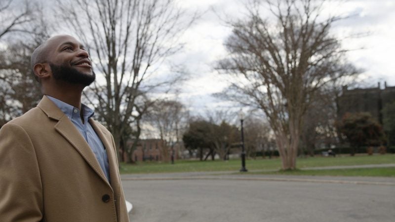 An alumnus of Georgetown returns to campus on a winter day and looks up at Healy Hall with a smile on his face.